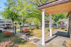 A covered outdoor area with a stone floor, a bench, and a white column.