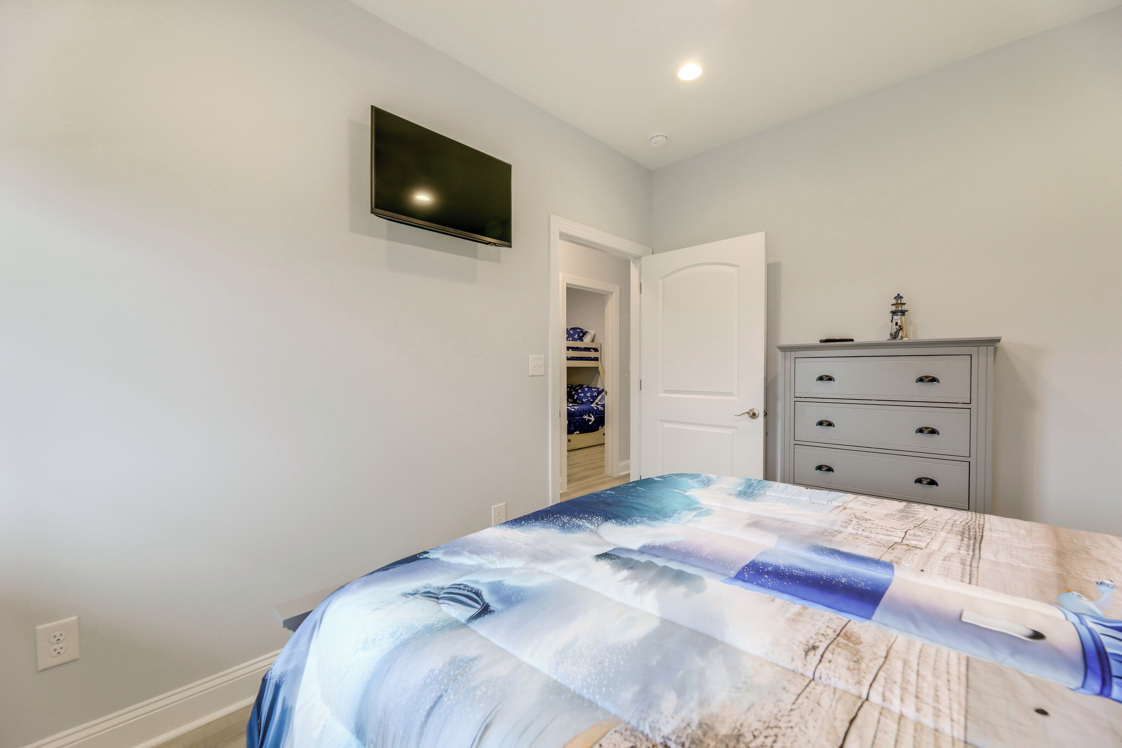 Une chambre à coucher comprenant un lit, une commode, un téléviseur et une porte donnant sur un placard.
