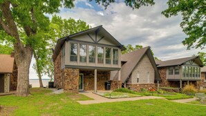 A two-story house with a stone facade, large windows, and a covered porch. - Water-view Patio, Near Golf! Port Duncan Retreat (Afton)