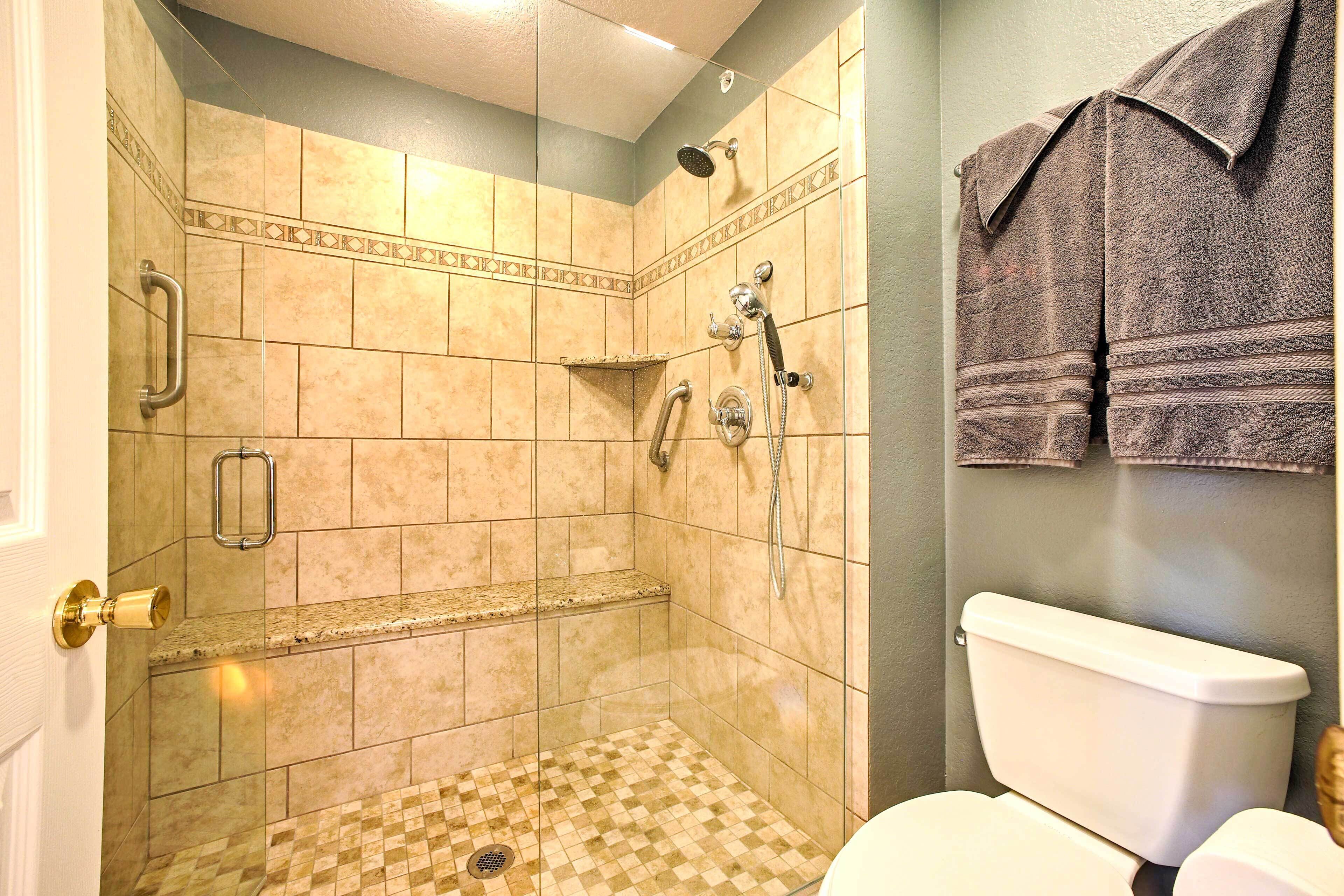 A bathroom with a shower, toilet, and towel rack.