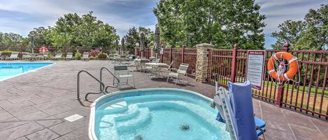 An outdoor swimming pool with lounge chairs and a lifebuoy, surrounded by a fence and trees.