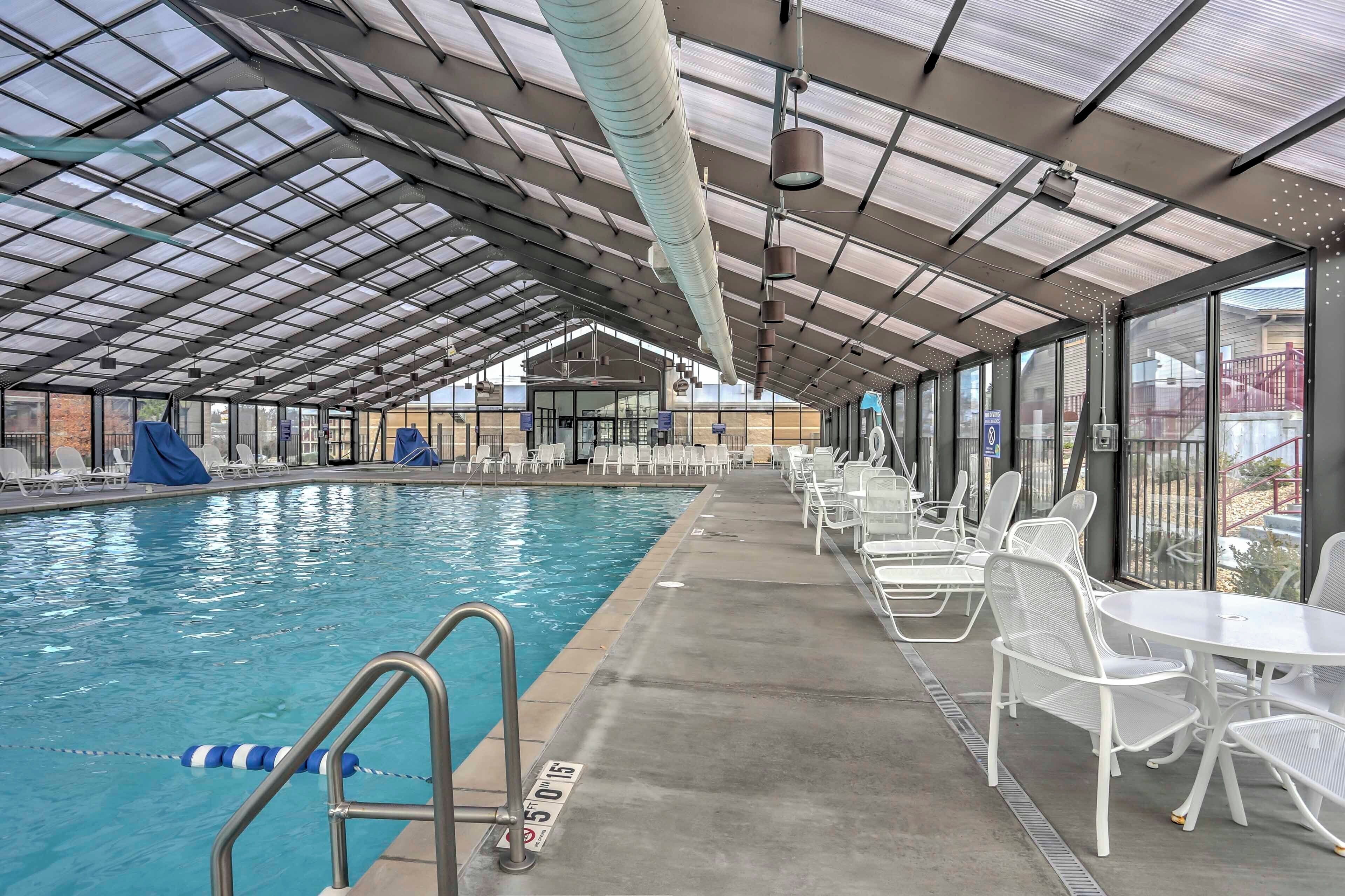 Ein Hallenbad mit überdachtem Bereich, klarem Pool und Sitzgelegenheiten mit Tischen und Stühlen.