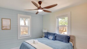 Un dormitorio con cama, ventilador de techo, ventanas y alfombra.