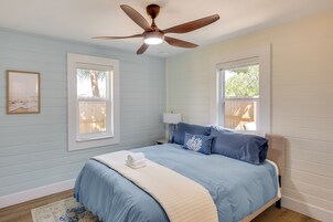 Un dormitorio con cama, ventilador de techo, ventanas y alfombra.