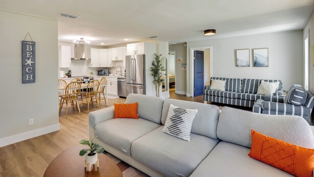 Una sala de estar moderna con un sofá gris, cojines naranjas y una mesa de centro redonda con una planta.