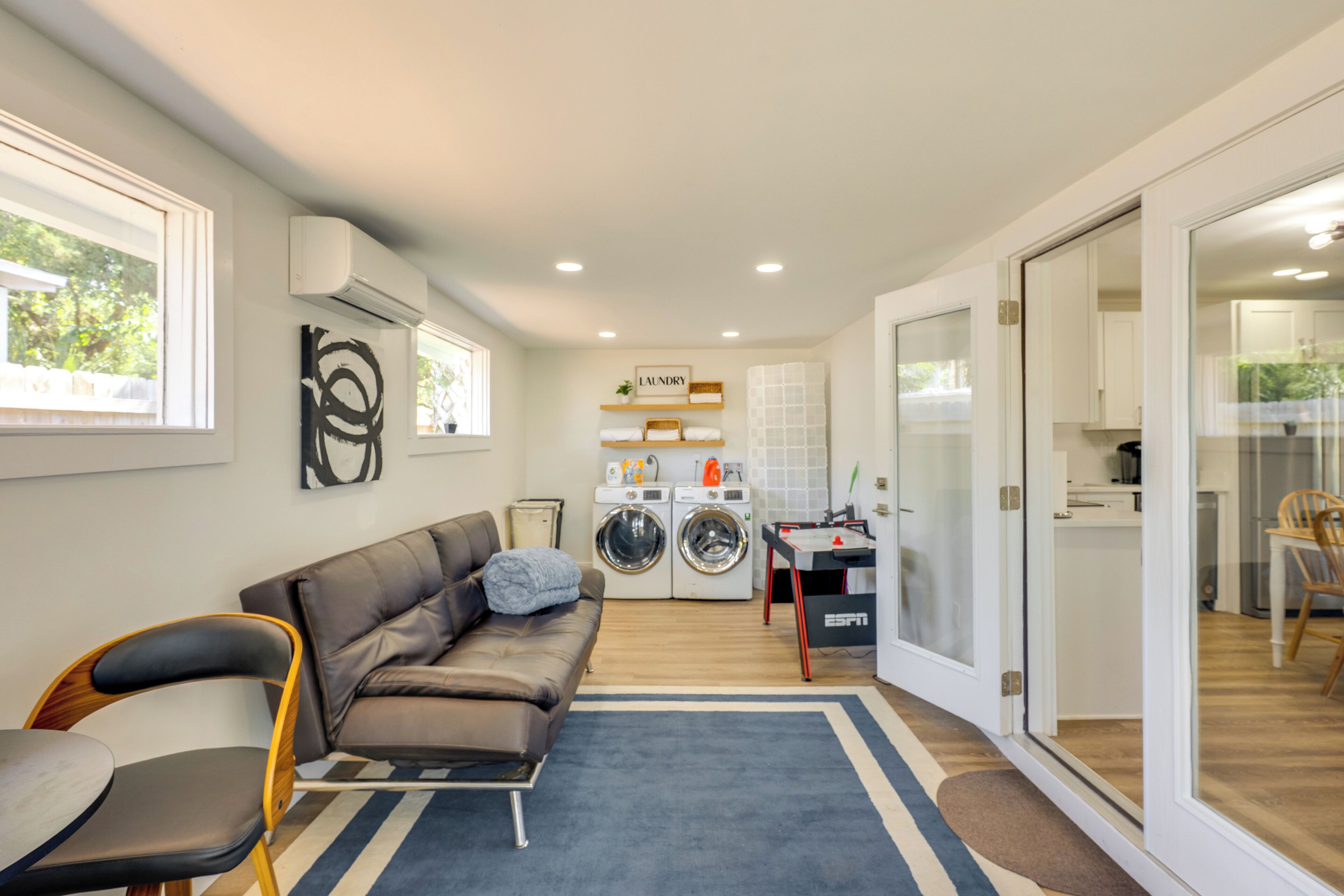 Un apartamento moderno con sala de estar, zona de lavandería y puerta de vidrio que da a un comedor.