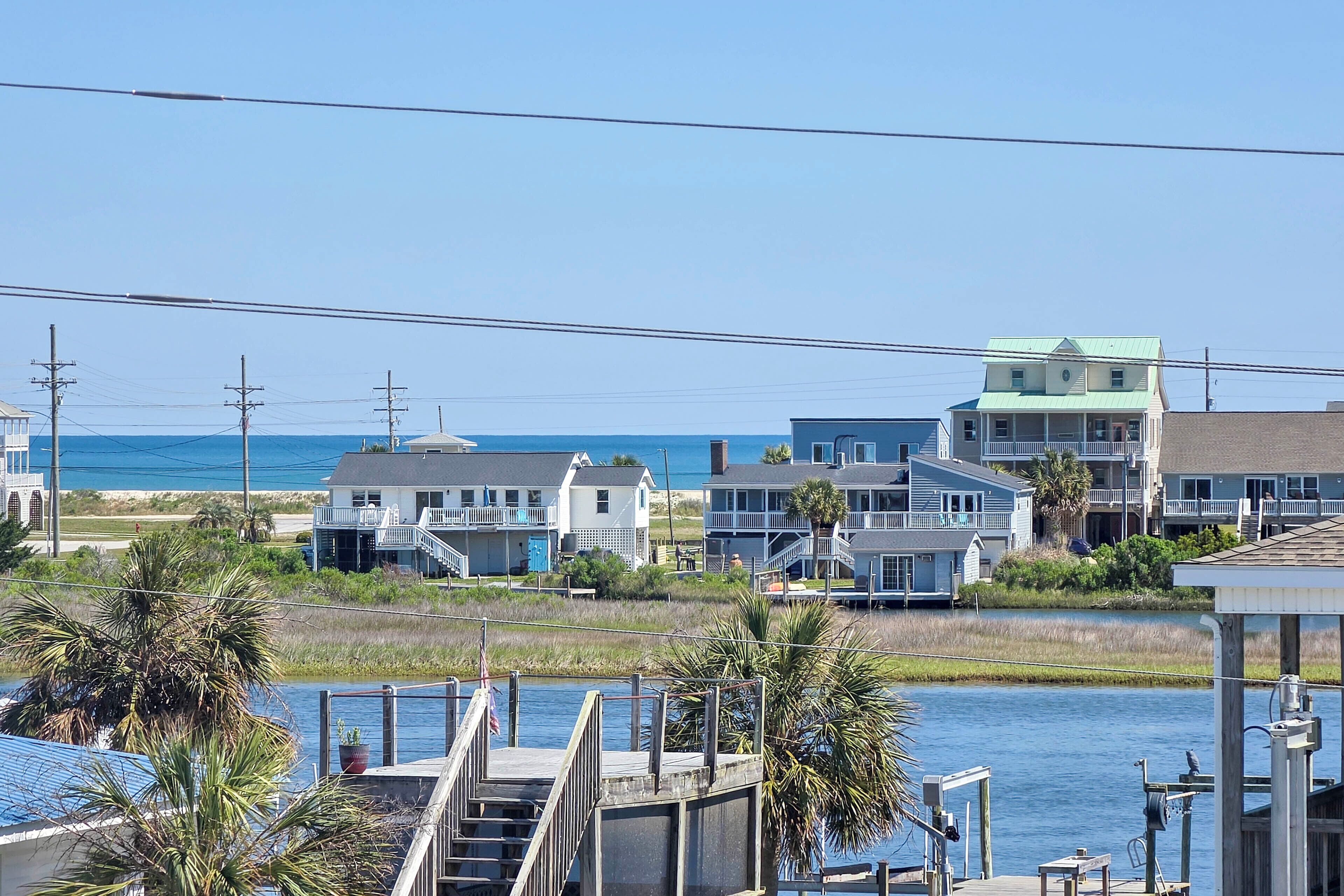 A coastal residential area with houses, a dock, and a clear view of the ocean.