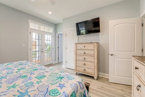 A bedroom with a bed, a dresser, a television on the wall, and a door. - Coastal Views & Hot Tub! Sneads Ferry Getaway (Sneads Ferry)