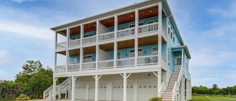 A multi-story building with balconies, a staircase, and a garage.