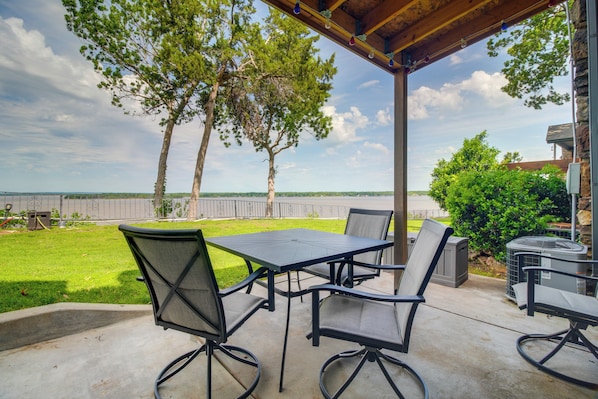 Eine Außenpatio mit Tisch und Stühlen, einem überdachten Bereich und Blick aufs Wasser.