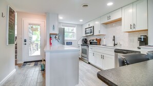 Une cuisine moderne avec des meubles blancs, un îlot central, un four à micro-ondes et un lave-vaisselle.
