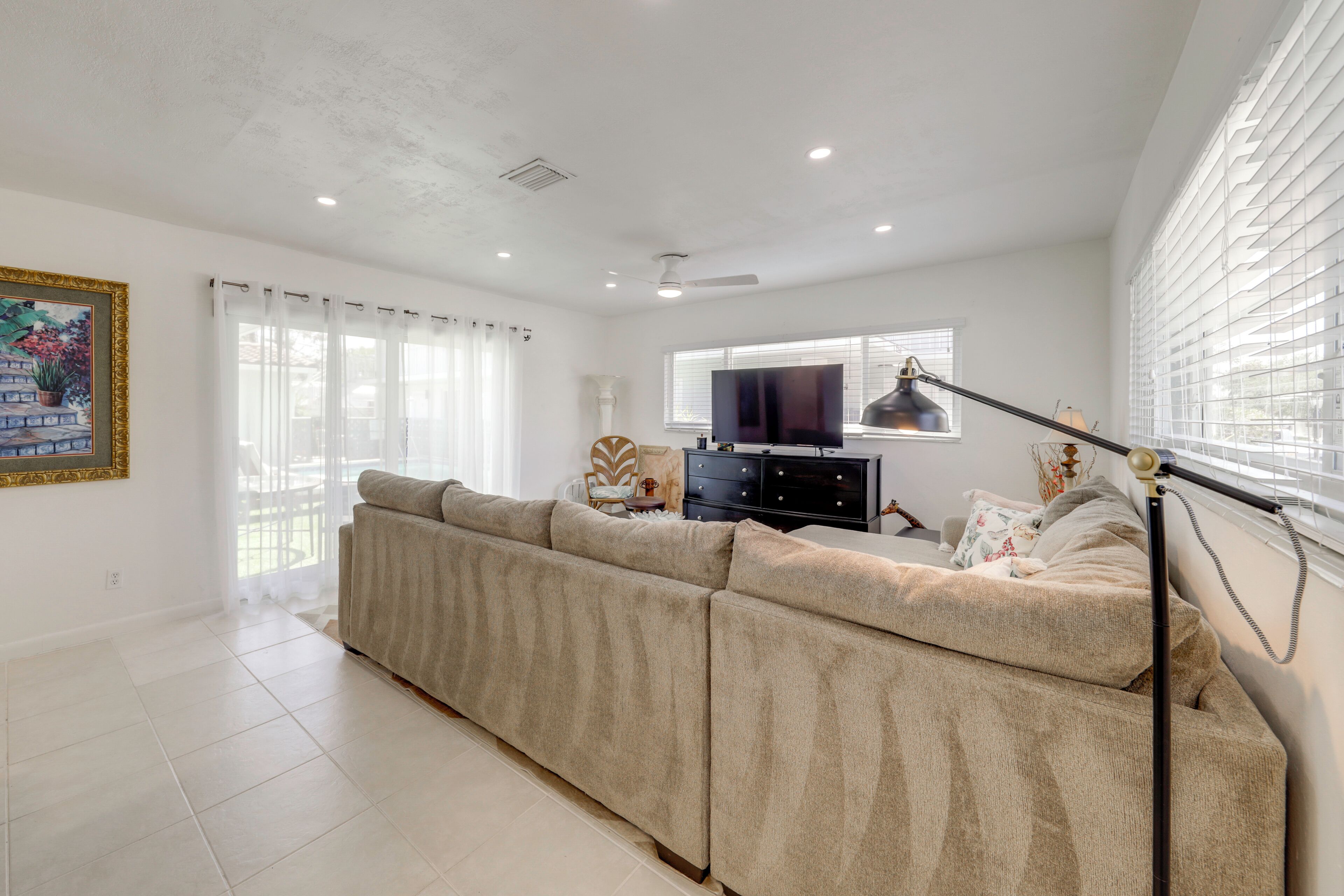 Una sala de estar con un sofá modular, un televisor y un ventilador de techo.