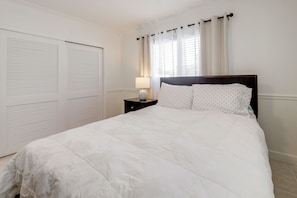 A bedroom with a bed, nightstand, lamp, and a window with curtains. - 1 Mi to Pompano Beach! Couples Retreat w/ Pool (Pompano Beach)