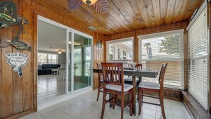 Una habitación con paneles de madera, una mesa de comedor, sillas y un puerta de cristal que da a una sala de estar.