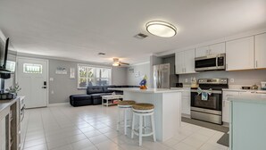 Una cocina moderna con gabinetes blancos, electrodomésticos de acero inoxidable y una isla central con taburetes.