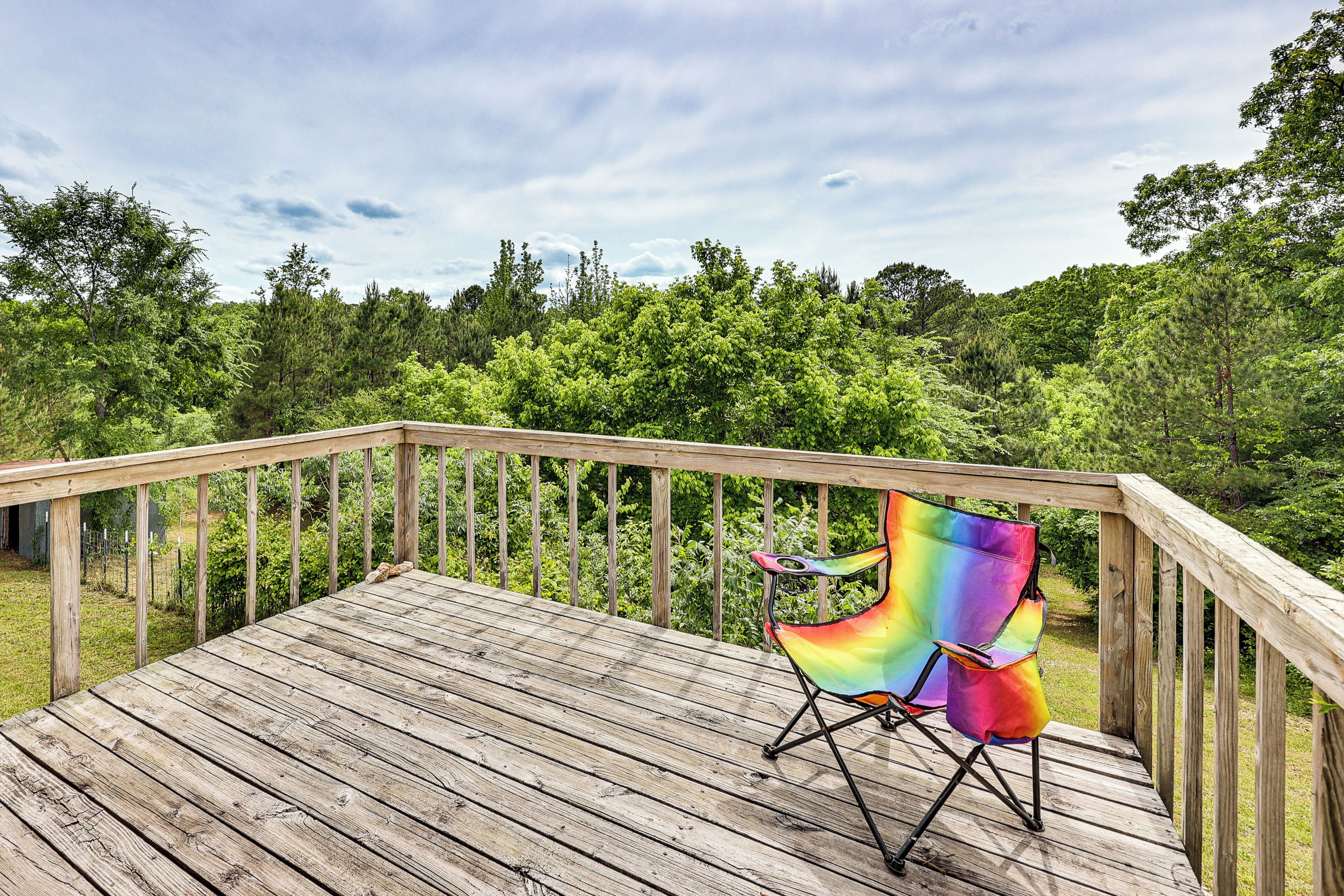 A wooden deck with a rainbow-colored folding chair.