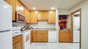 Una cocina con armarios de madera, microondas, estufa, lavavajillas y un fregadero.