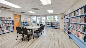 Et bibliotek med et rundt bord og stole, omgivet af reoler.
