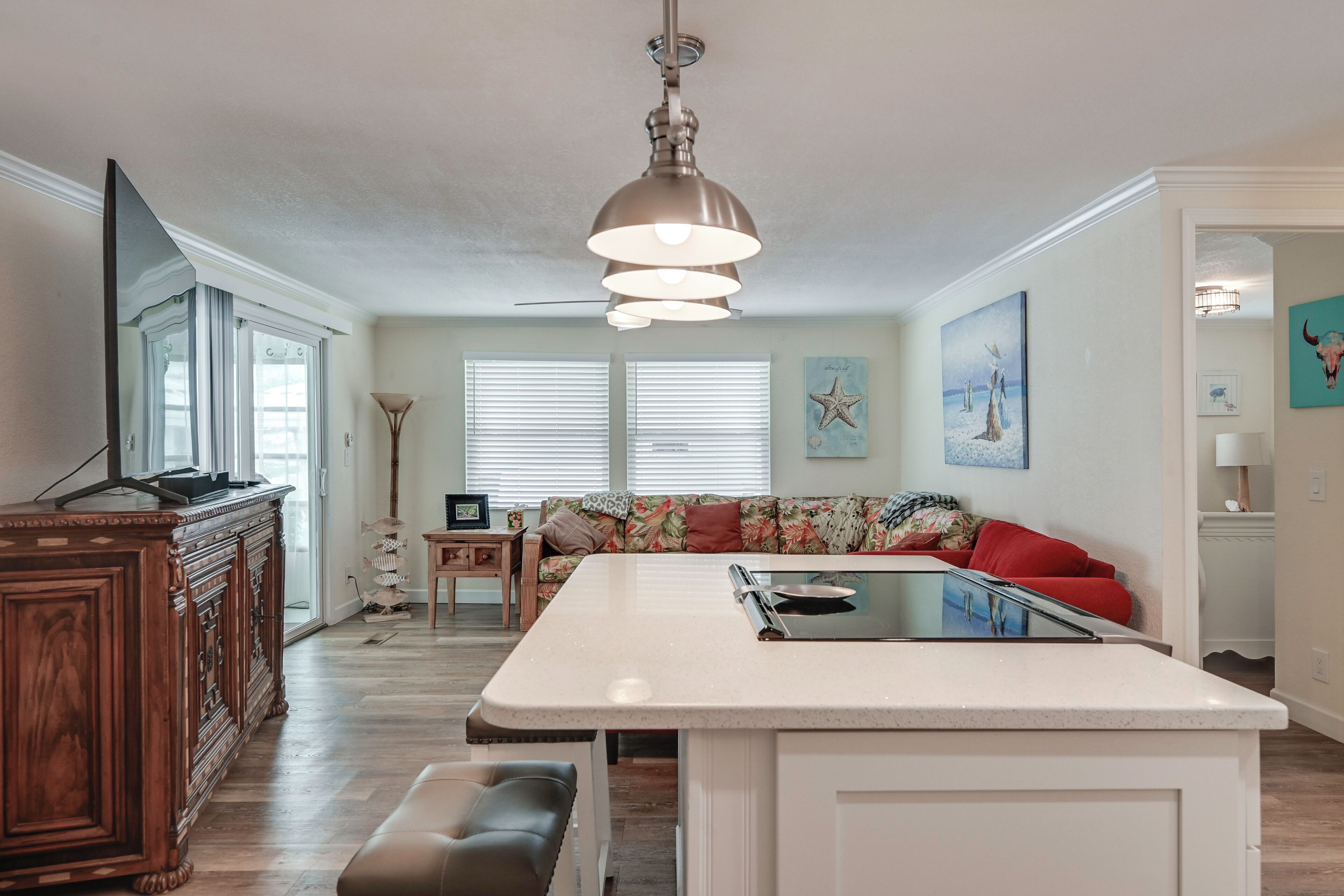 A modern kitchen with a central island, wooden cabinetry, and a ceiling fan.