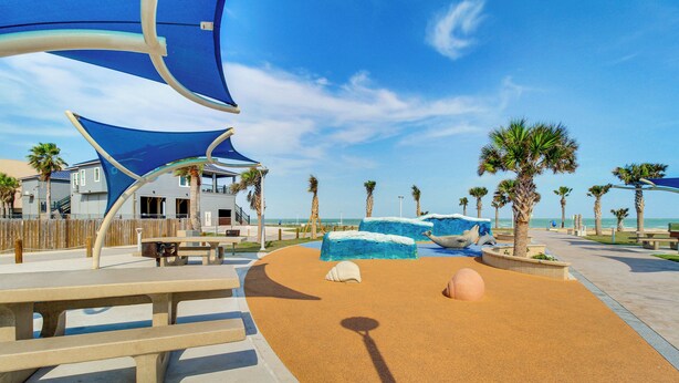 A beachside park with shaded seating, palm trees, and a sandy play area. - Poolside Fun, Ocean Strolls! Corpus Christi Escape (Corpus Christi)