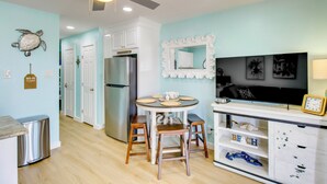 A kitchen with a ceiling fan, a refrigerator, a dining table with stools, and a wall-mounted mirror. - Poolside Fun, Ocean Strolls! Corpus Christi Escape (Corpus Christi)