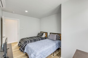 Une chambre avec deux lits, une télévision et un plancher en bois.