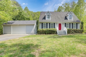 A two-story house with a garage, a red front door, and a small staircase leading to the front porch.