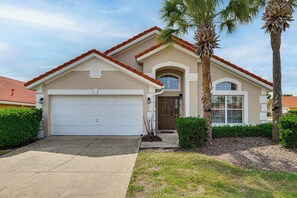 A two-story house with a garage, a front door, and a small porch. - Near Disney & Universal: Home w/ Pool & Spa! (Davenport)