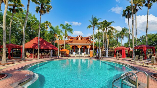 A swimming pool with a no diving sign, surrounded by palm trees and a building with a red roof. - Near Disney & Universal: Home w/ Pool & Spa! (Davenport)