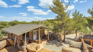 A stone building with a covered patio, large rocks, and a wooden fence.