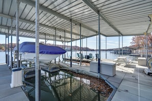 A covered dock area with a boat, seating, and a view of the water and hills. - 2 Units w/ Boat Dock & Slip Access in Lake Ozark! (Lake Ozark)