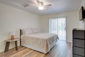 A bedroom with a bed, a ceiling fan, a nightstand, a lamp, a window with blinds, and a TV mounted on the wall. - Steps to Crystal River! Dual-unit w/ Patios & Yard (Crystal River)