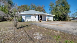 A single-story house with a front door, a small porch, and a driveway. - Steps to Crystal River! Dual-unit w/ Patios & Yard (Crystal River)