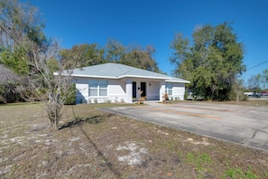 A single-story house with a front door, a small porch, and a driveway. - Steps to Crystal River! Dual-unit w/ Patios & Yard (Crystal River)