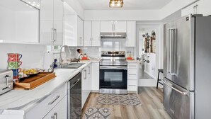 Una cocina moderna con armarios blancos, electrodomésticos de acero inoxidable y una alfombra estampada.