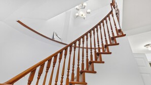Una escalera con barandilla de madera y pared blanca.