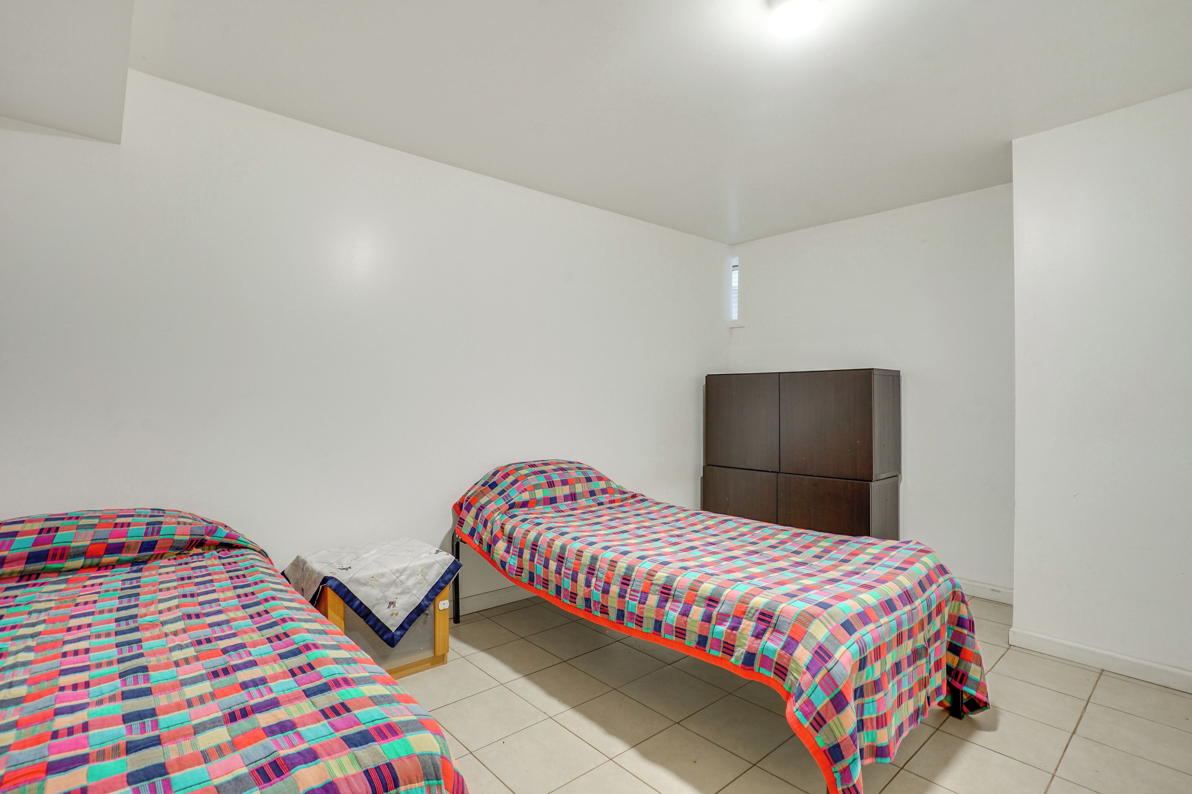 Une chambre avec deux lits simples, une petite table et une armoire.