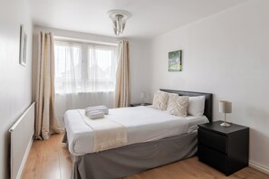 Ein Schlafzimmer mit Bett, Nachttisch und Fenster mit Vorhängen.
