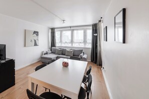 Ein modernes Wohnzimmer mit einem weißen Sofa, einem Esstisch und einem Fernseher.
