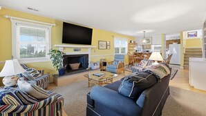 Een woonkamer met een open haard, bank, fauteuil en een televisie.
