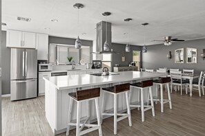 A modern kitchen with a central island, bar stools, stainless steel appliances, and pendant lighting. - Private Heated Pool Perfect for Groups (Peoria)