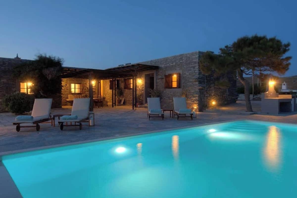 A stone building with a pool and lounge chairs.