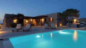 A stone building with a pool and lounge chairs.