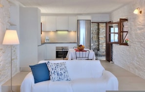 A modern interior with a white sofa, a dining table, and a kitchen area.