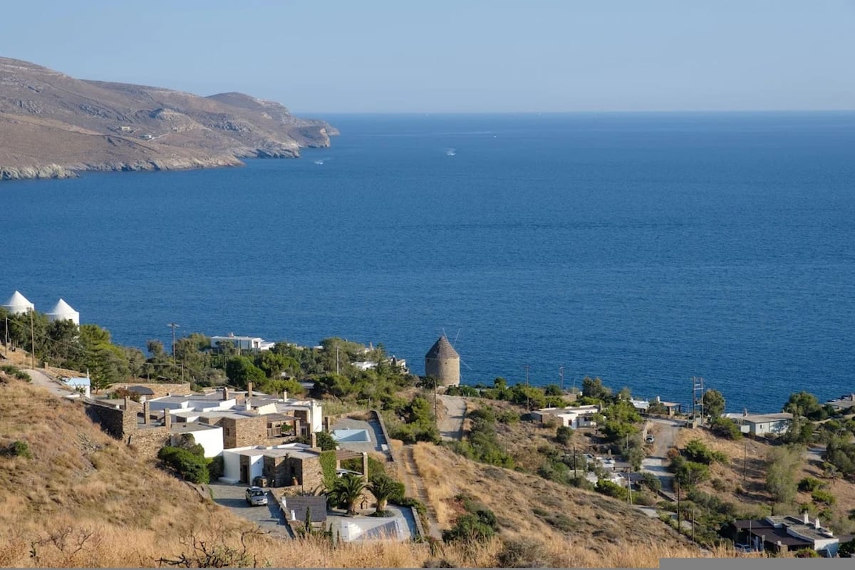 A coastal village with traditional architecture, including a prominent tower, and a clear view of the sea.