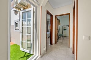 Porta a vetri scorrevoli aperta che dà su una stanza con pavimento piastrellato, stipite in legno e un interruttore della luce in vista.