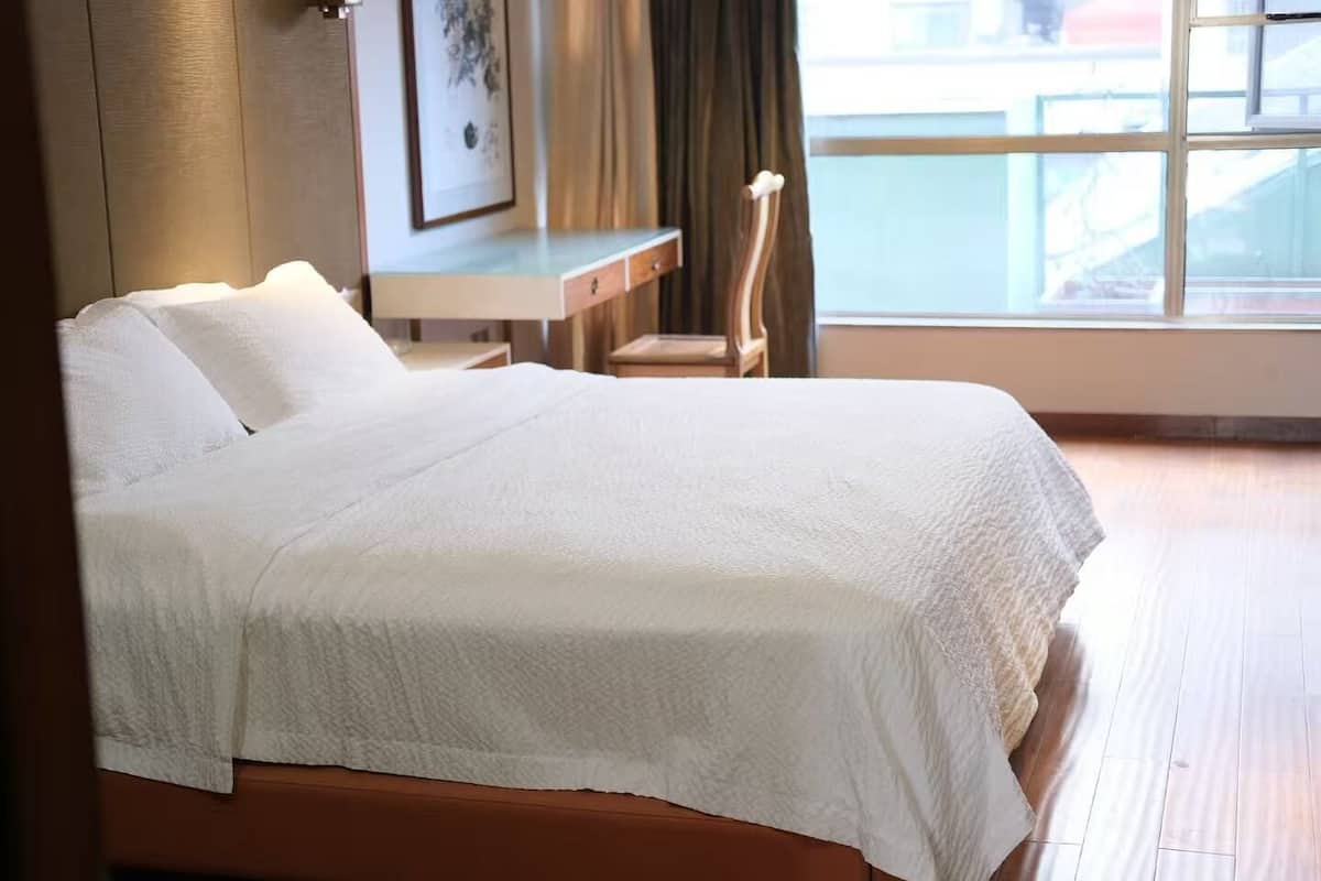 A hotel room with a bed, a desk, and a chair.