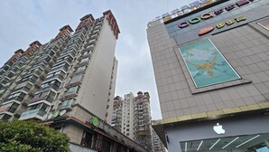Um edifício com vários andares e varandas, uma loja com o logotipo grande da Apple e uma placa indicando a loja G Share.