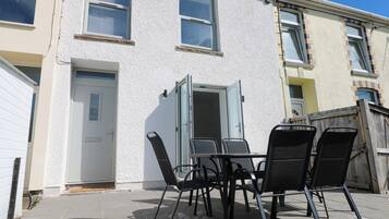 A patio with a table and chairs, a white door, and a window with blinds.