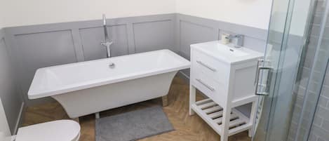 Ein Badezimmer mit einer weißen Badewanne, Toilette, Waschbecken und Dusche.
